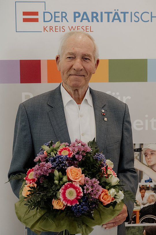 Geehrter mit Blumenstrauß und Urkunde